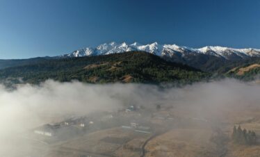 A breathtaking view of a misty valley with snowy mountains in Kargong, perfect for nature and travel enthusiasts.