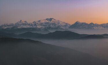 Beautiful sunrise view of the snow-covered Himalayas in Sikkip, India, with misty valleys and a scenic backdrop.