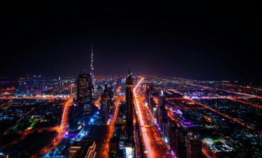 A breathtaking aerial view of Dubai's cityscape at night, highlighting the illuminated Burj Khalifa and surrounding skyscrapers.