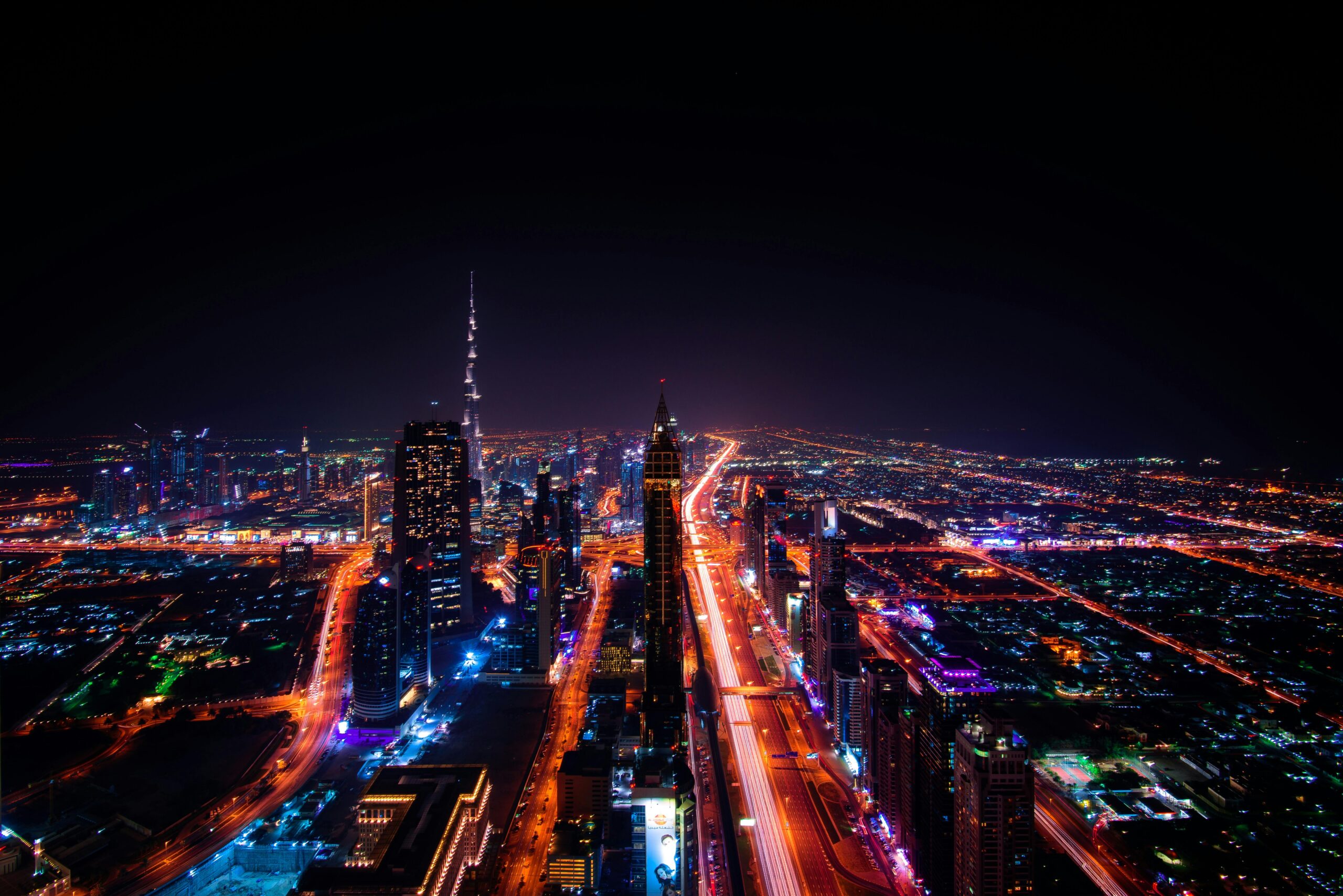 A breathtaking aerial view of Dubai's cityscape at night, highlighting the illuminated Burj Khalifa and surrounding skyscrapers.