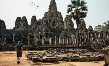 Traveler exploring the ancient Bayon Temple at Angkor Thom, Cambodia, surrounded by stunning architecture.