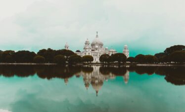 Stunning reflection of Victoria Memorial in Kolkata on a serene lake with clear skies.