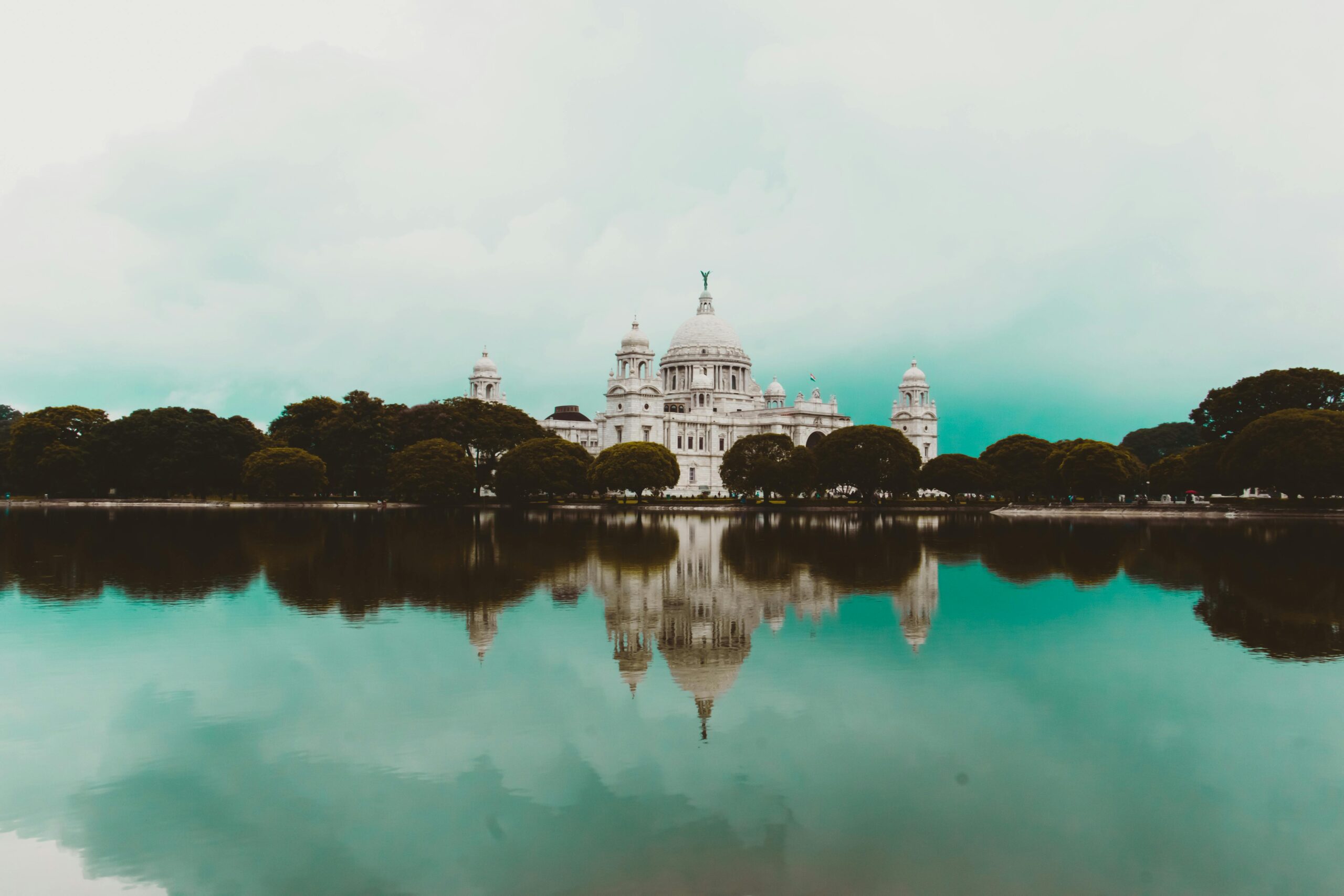 Stunning reflection of Victoria Memorial in Kolkata on a serene lake with clear skies.
